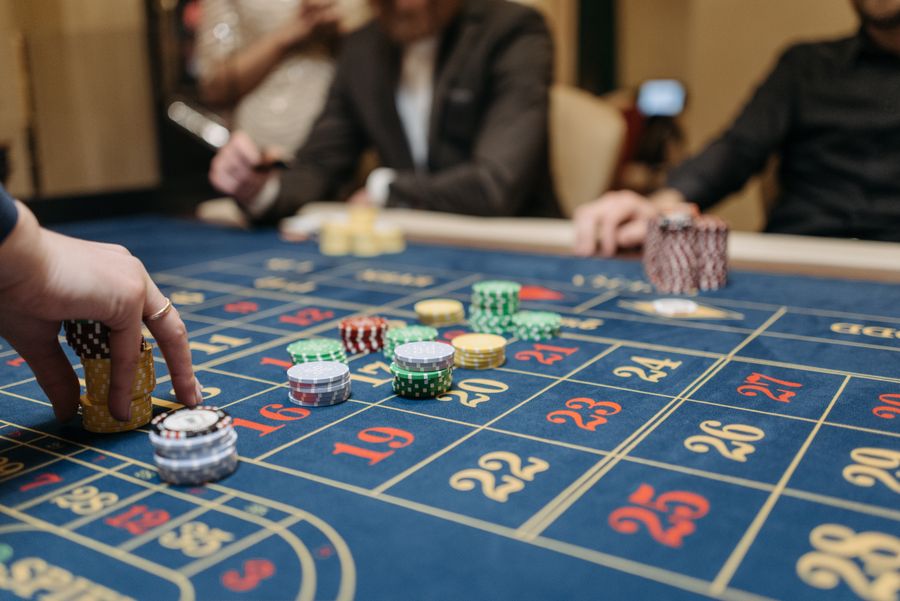 Tangan pemain menempatkan chip di atas meja roulette kasino